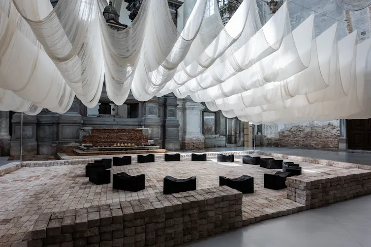 White sheets billow as a roof above a circle of black benches.