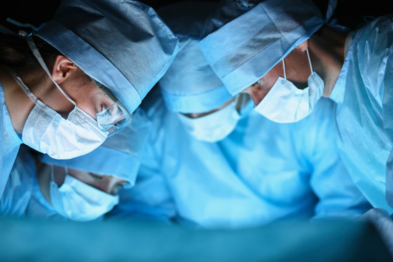 Surgeons looking down at a patient.