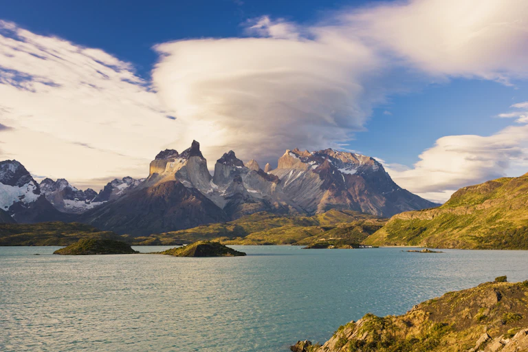 Clouds over a rocky coastline. One over mountains is circular.