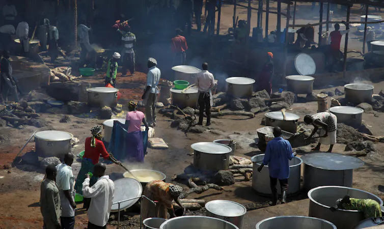 A group of people cooking large pots of maize porridge.