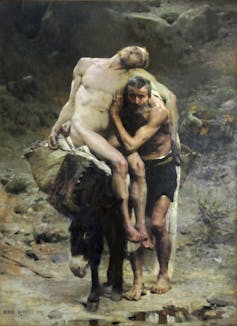 A painting with muted colors shows an elderly man walking alongside a mule as he props up a faint, naked man sitting on the animal.