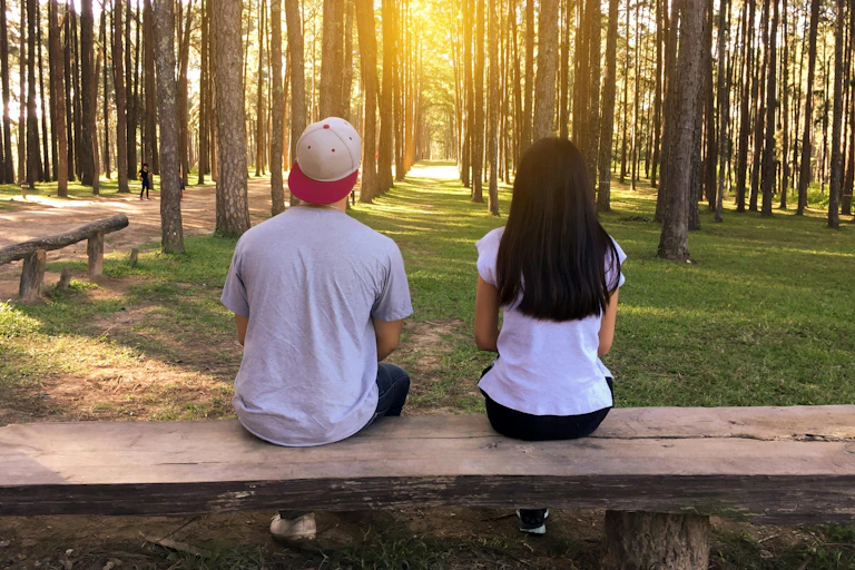 A young man and young woman its next to each other on a bench.