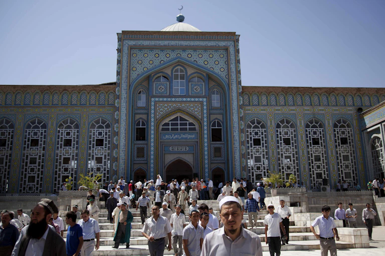 People walk down steps in front of a building with ornate blue tiles.