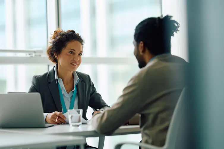 Human resource manager communicating with candidate across desk during job interview