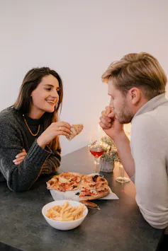 A couple shares a meal featuring pizza, fries, and drinks