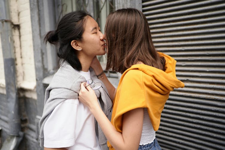 Two young people kiss on a street.