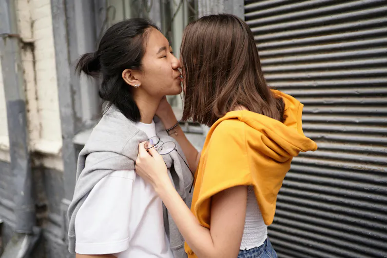 Two young people kiss on a street.
