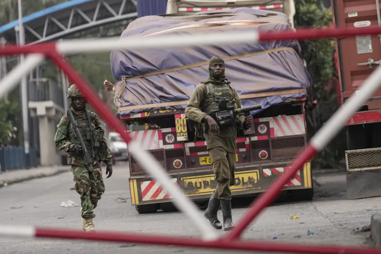 Men in military fatigues walk near a lorry at a checkpoint