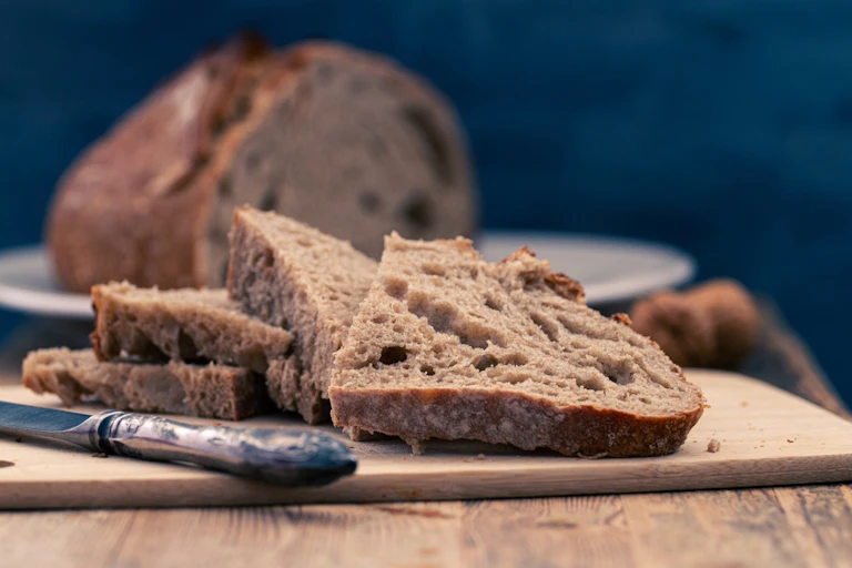 Slices of rustic, sliced brown, wholemeal or wholegrain bread on wood board with knife