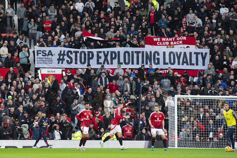 Football fans at match holding banner which reads: 'STOP EXPLOITING LOYALTY'.