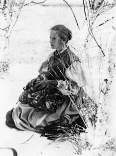 Black and white photo of a young Helen Mirren sat in the snow.