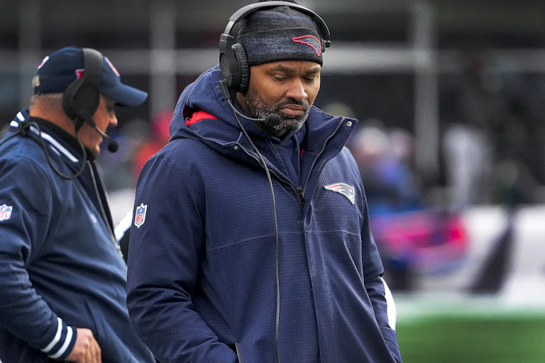 A Black man wearing a headset walks with his head down.
