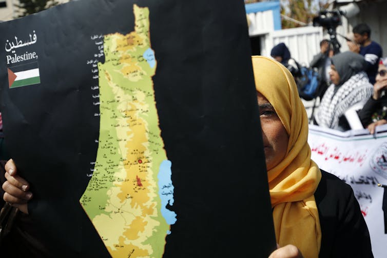 A woman in a headscarf holds up a map