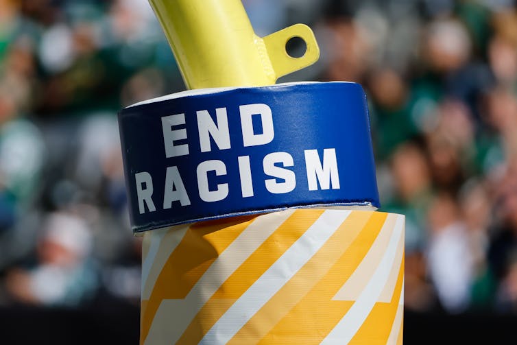 A pad with the words End Racism is attached to a goal post during a professional football game.