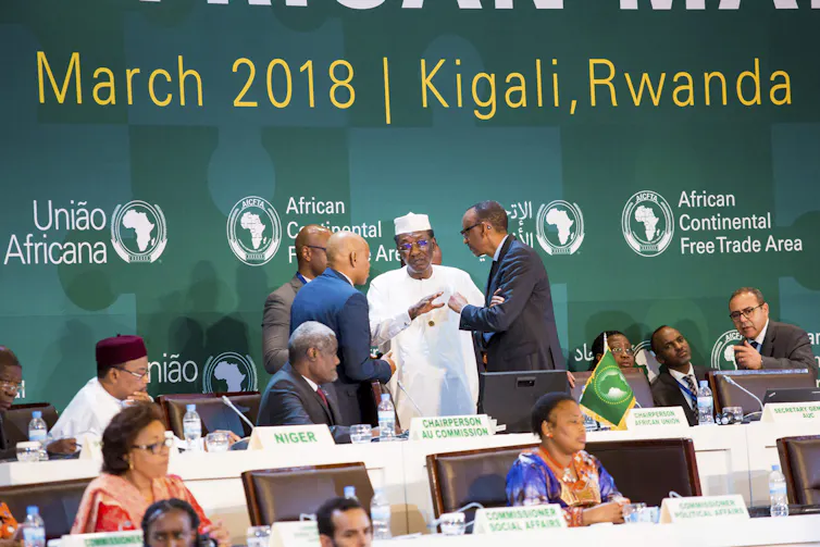 Leaders gather at a conference with a green banner behind them that reads March 2028/Kigali, Rwanda.