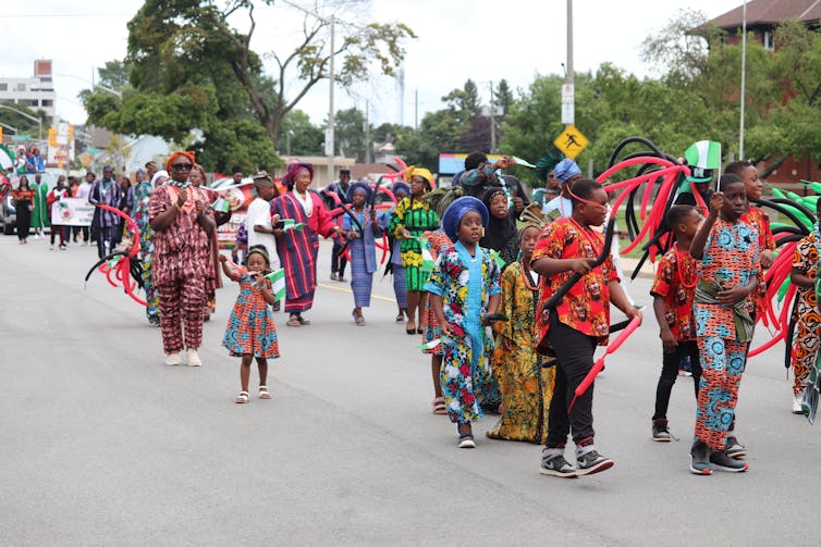 Black people in colorful clothes march in parade.