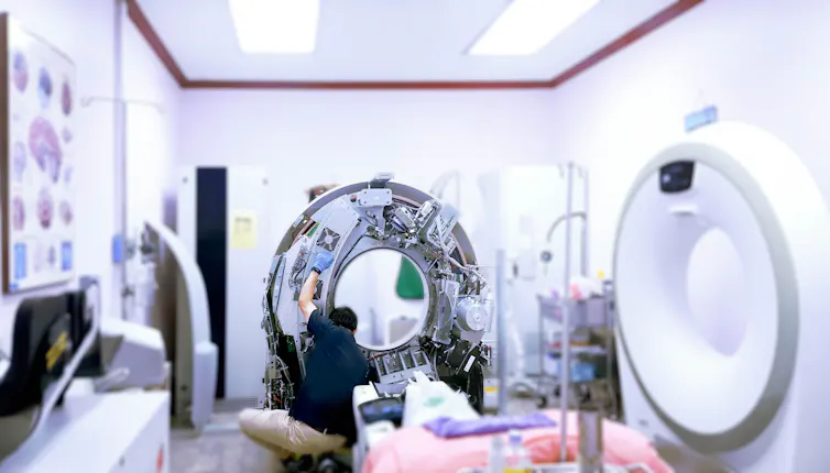 A person looks at the inside of a CT scanner machine in a hospital room