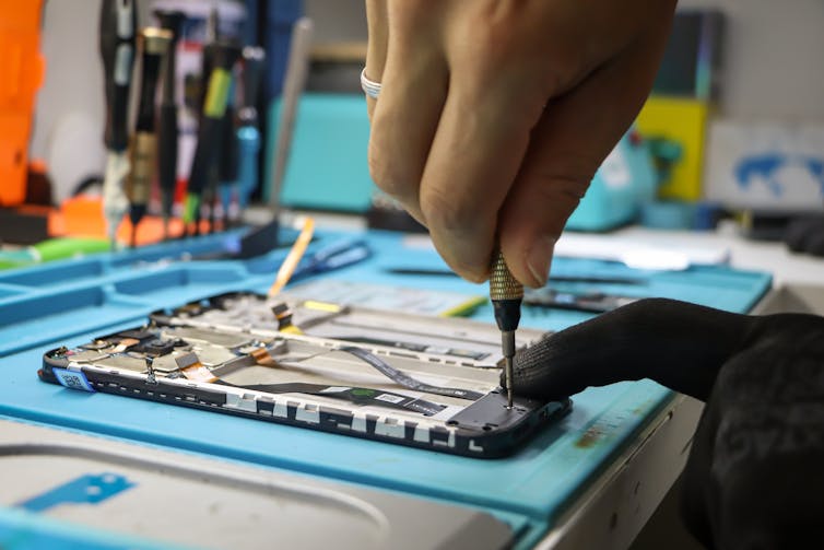 Close-up of a pair of hands unscrewing part of the back plating of a smartphone