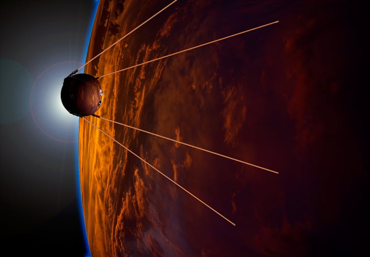 Small circular spacecraft with four antennas flying past an orange planet.