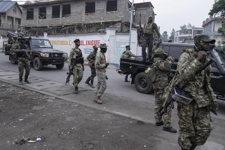 Men in military fatigues walking along a road carrying assault rifles