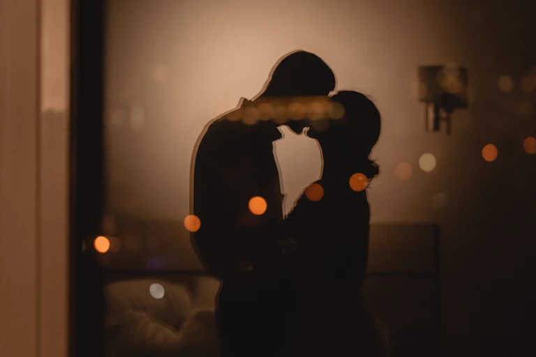 A silhouette of a couple kissing.
