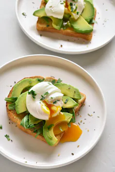 Poached eggs on toasted bread with avocado and herbs.
