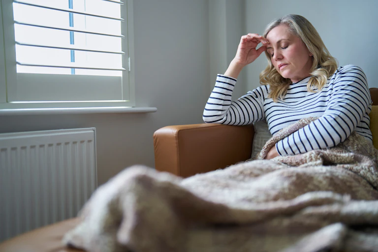 A woman with long COVID sits in a chair looking tired.