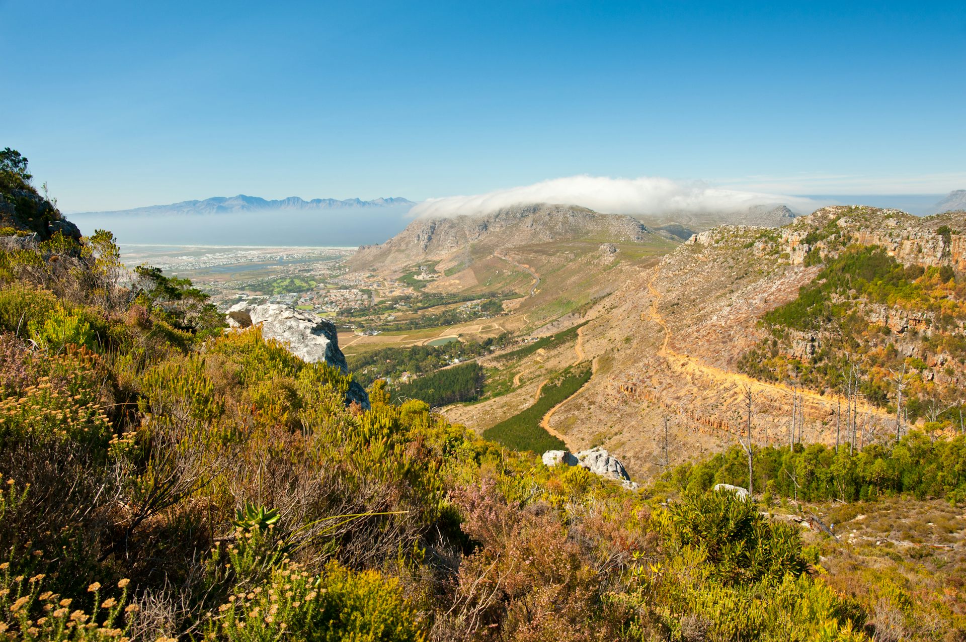 View from a mountain top, looking down to a city and away to distant mountains