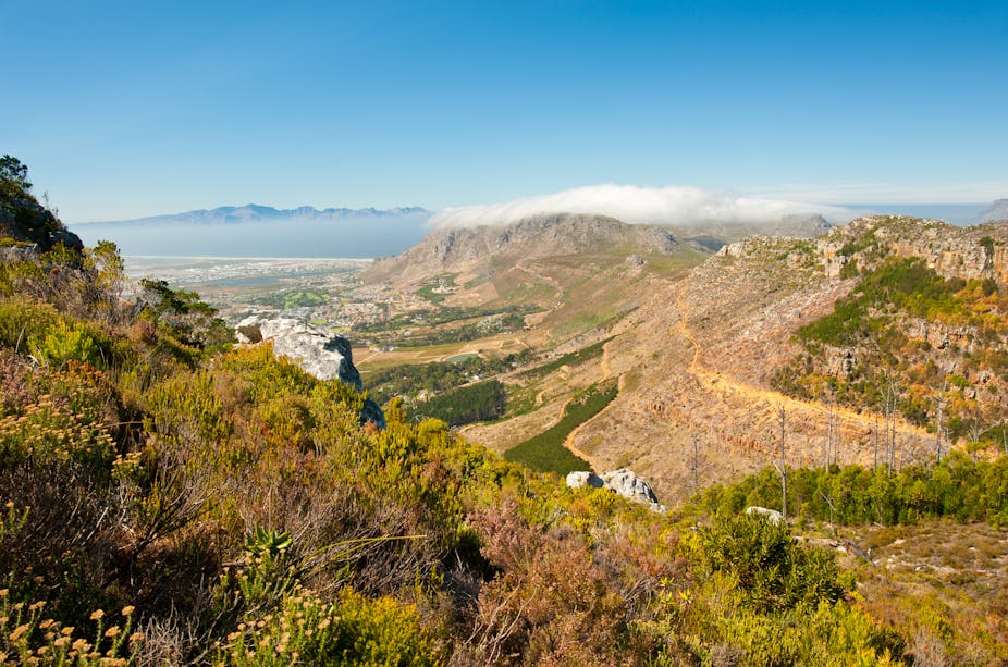 View from a mountain top, looking down to a city and away to distant mountains