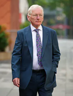 Man in suit walking in street near Manchester Crown Court.