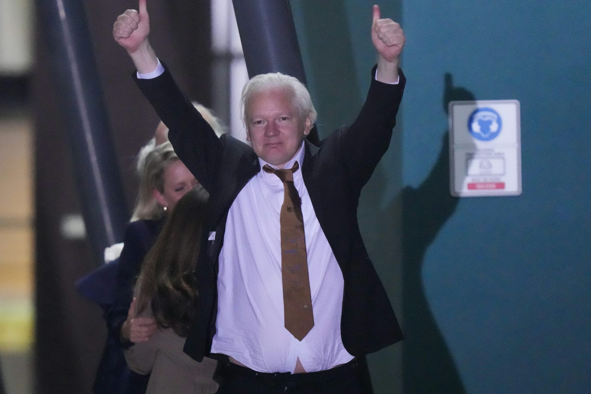 A man with white hair raises his arms in a celebratory gesture.