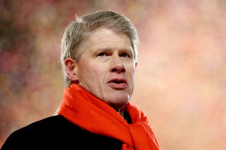 Portrait of middle-aged man with whitish-blonde hair and a thick, red scarf.