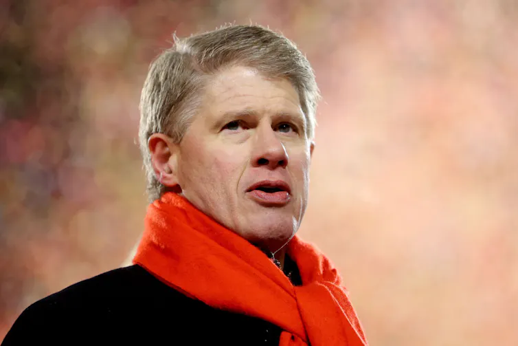Portrait of middle-aged man with whitish-blonde hair and a thick, red scarf.