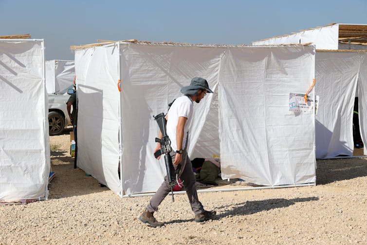 An armed Israeli settler patrols a temporary shelter built to host a conference about resettling Gaza in October 2024.
