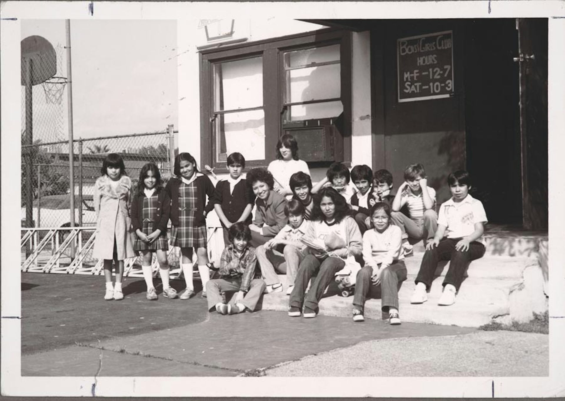 Black and white photo of an Asian woman surrounded by schoolchildren.