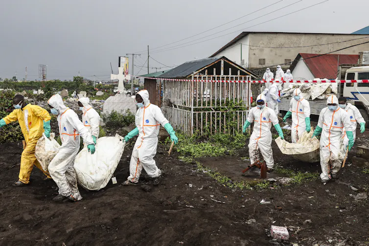 Volunteers carry bodies to a cemetery.