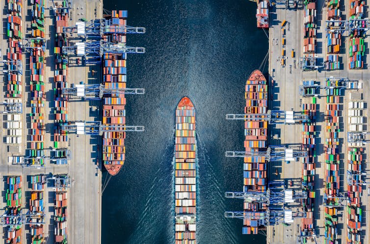 Aerial top down view of a large container cargo ship terminal with loading activity and vessel traffic