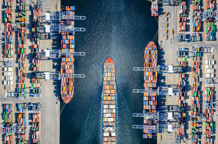 Aerial top down view of a large container cargo ship terminal with loading activity and vessel traffic