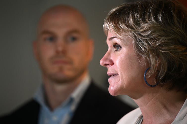 David Pocock standing in the background behind Zali Steggall who is in profile