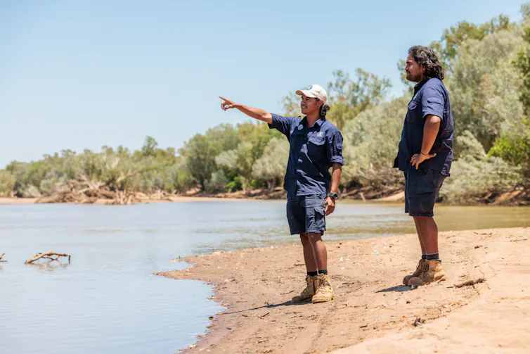 two Indigenous Rangers on the banks of a river