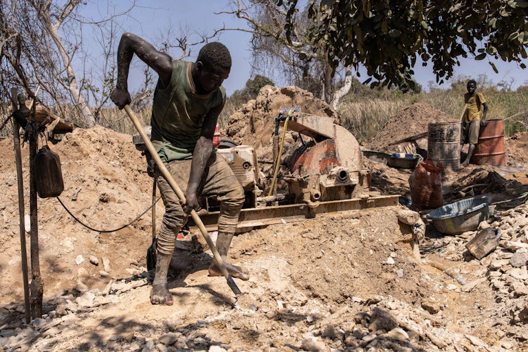 A barefoot man digging with a spade