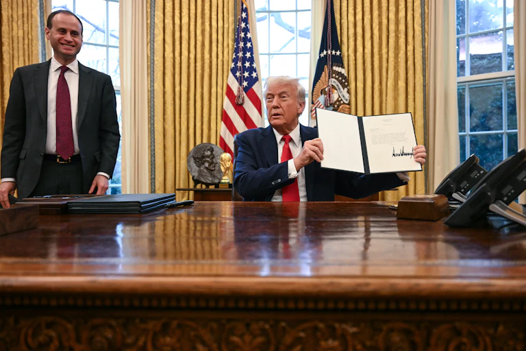 A man holds a folder with a large signature on it.
