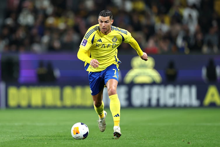A man in a yellow jersey runs toward a ball.