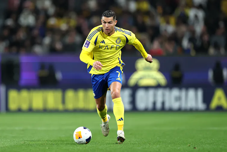A man in a yellow jersey runs toward a ball.
