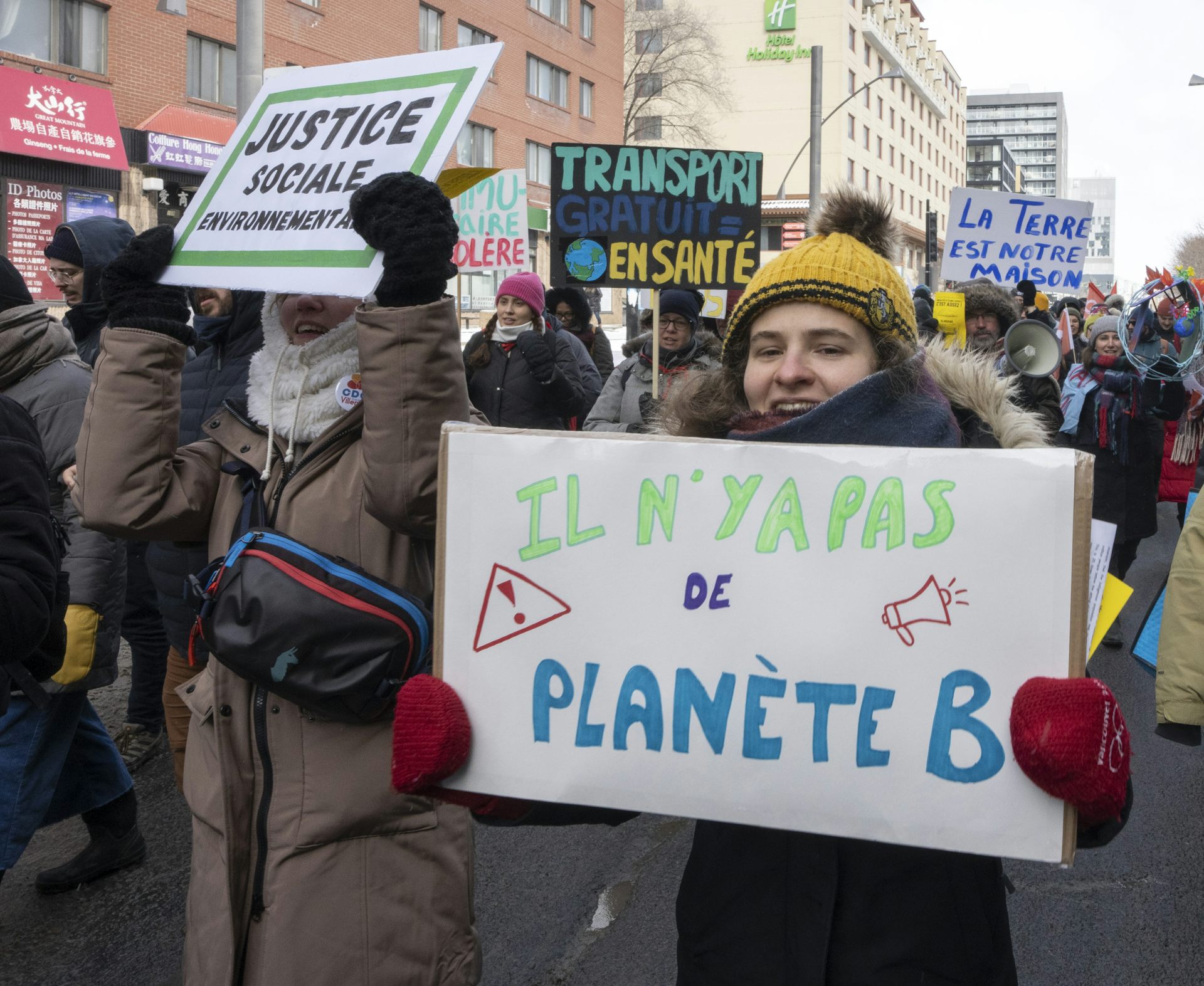 Des gens tiennent des affiches en marchant dans la rue.