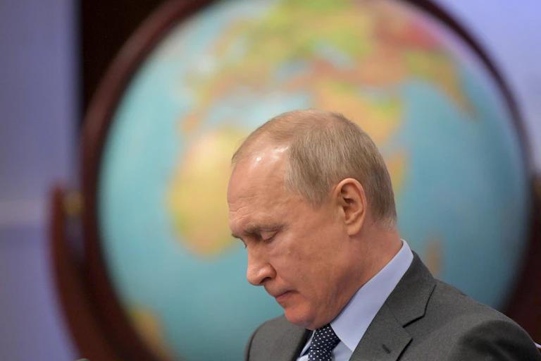 A man looks downward in front of a large globe.