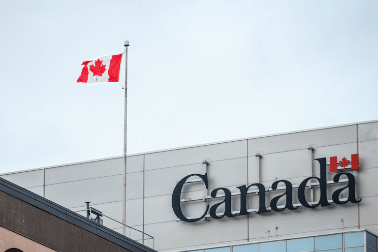A Canadian flag flies next to a building that says Canada on it