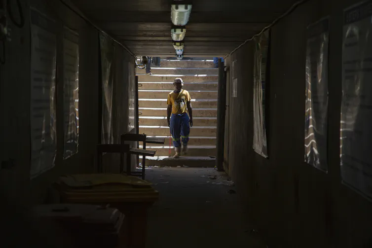 A man in a yellow t-shirt walks at the entrance of a mine shaft