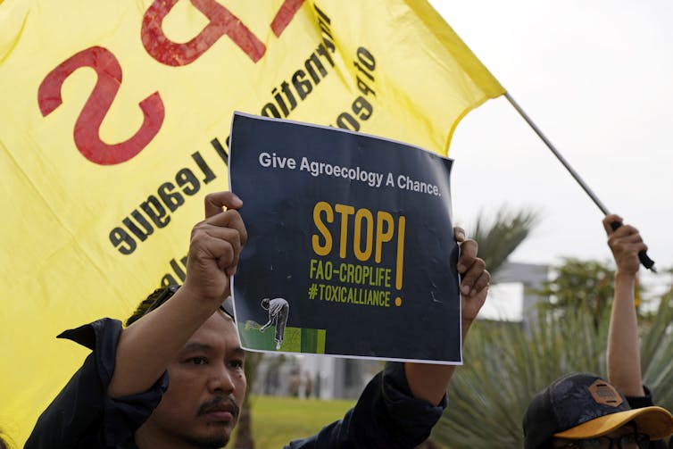 A demonstrator holds a sign that reads 'give agroecology a chance.'