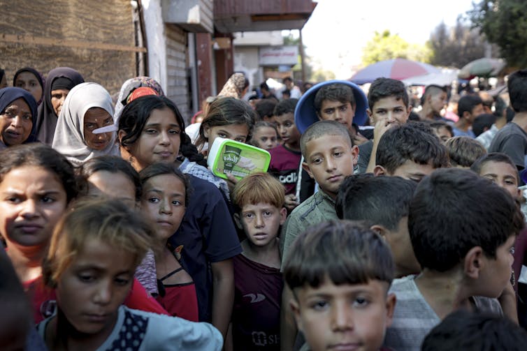 A group of mostly children line up for food.